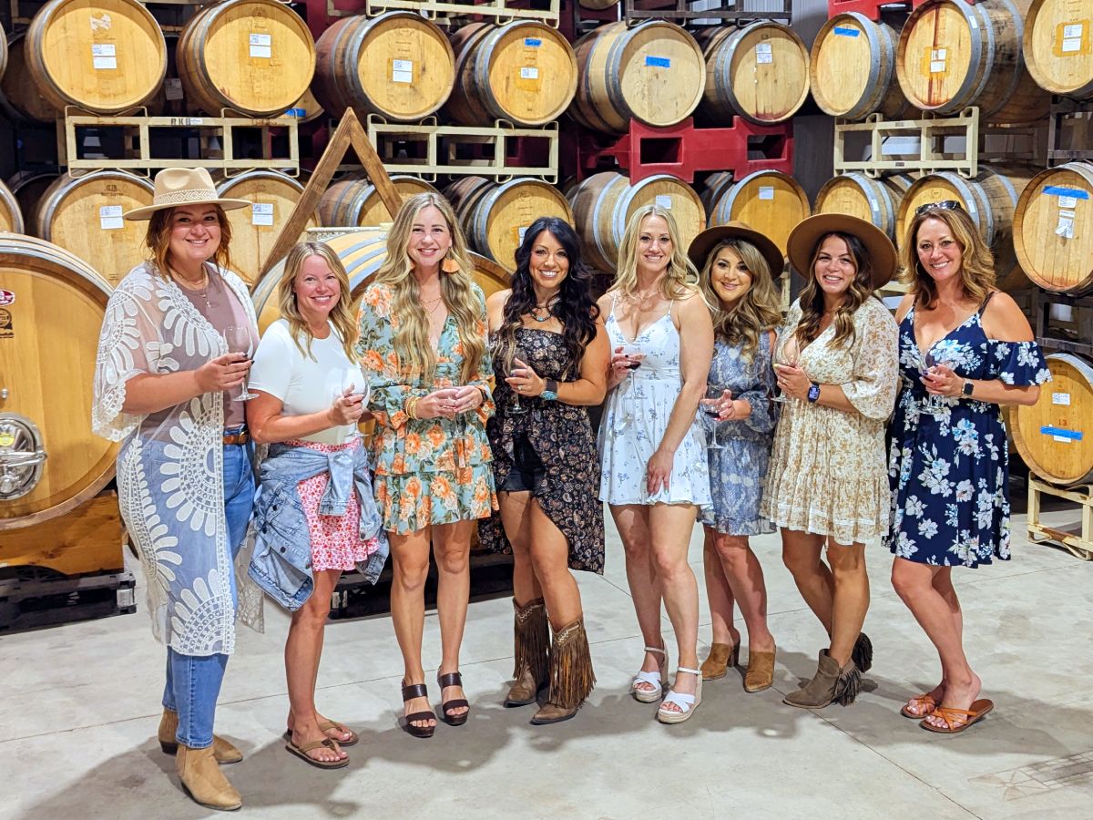 Tour group holding wine glasses in a barrel room